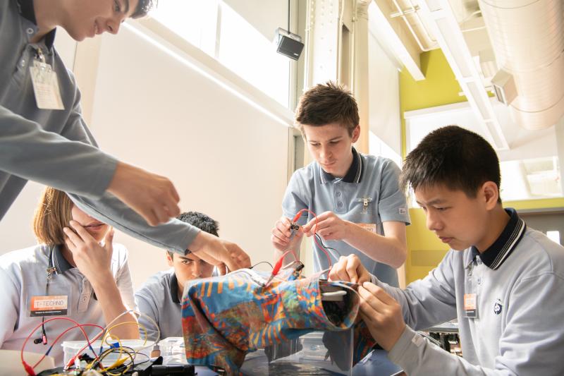 Five teenagers concentrated creating a prototype of smart clothing.